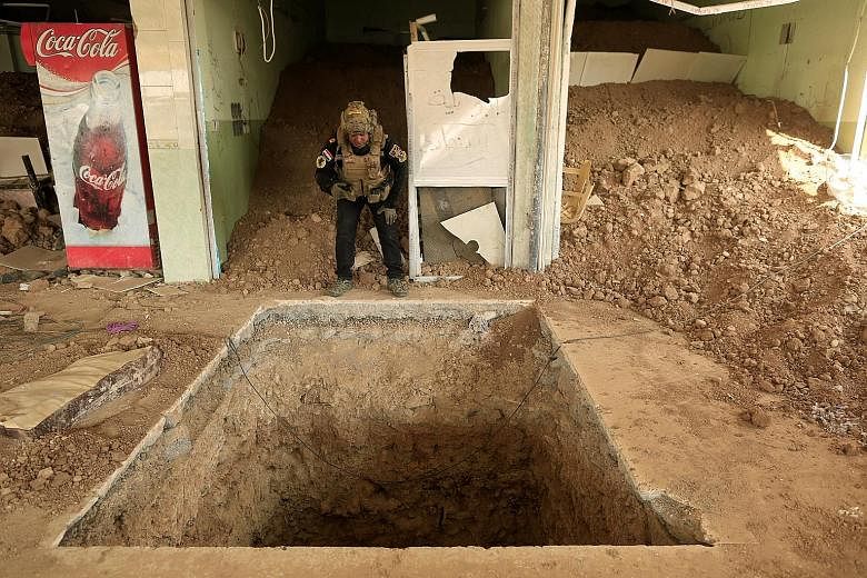 An Iraqi special forces soldier (right) climbs down a tunnel used by Islamic State in Iraq and Syria militants inside a house in the town of Bartalla, east of Mosul, while another soldier (above) inspects a similar tunnel inside an eatery in Bazwaia 