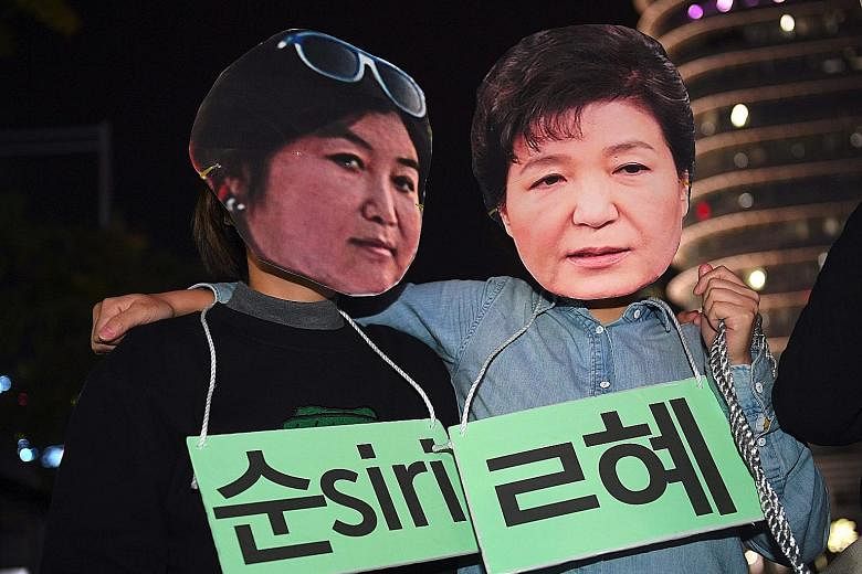 Protesters wearing masks of Ms Choi (far left) and Ms Park at a rally against the President's adviser in Seoul.