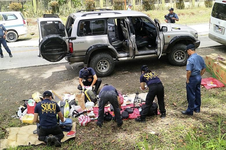 Police investigators collecting evidence at the scene of the shoot-out in Makilala, in southern Philippines, yesterday. The mayor of Datu Saudi Ampatuan, Mr Samsudin Dimaukom, and nine others were killed before dawn in a gun battle with anti-narcotic