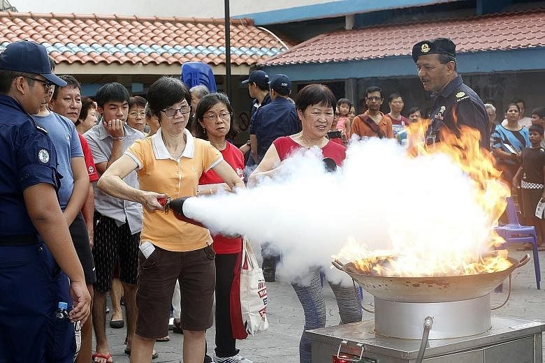 Singapore Civil Defence Force officers teaching residents in Bedok how to use fire extinguishers yesterday during Emergency Preparedness Day. Officers responding to a "shooting attack" at a crowded market and food centre in Bedok yesterday, in an eme