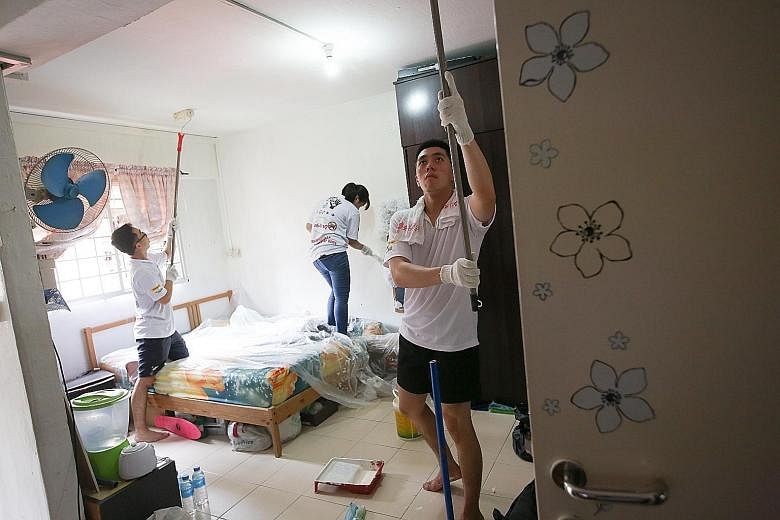 Volunteers (from left) Cheng Wen Jie, Leow Hua Hui and Rexmond Lim, all aged 21, painting the walls and ceiling of a flat at Block 106 Jalan Bukit Merah yesterday.