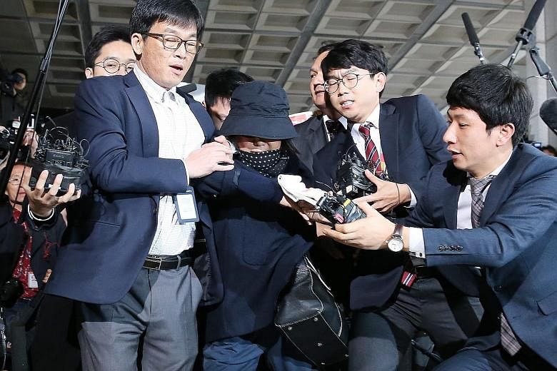 Ms Choi (wearing a hat) turned up at the Seoul Central District Prosecutor's Office yesterday, making her way through a mob of journalists. She is accused of using her close friendship with President Park to exert extensive influence over major gover
