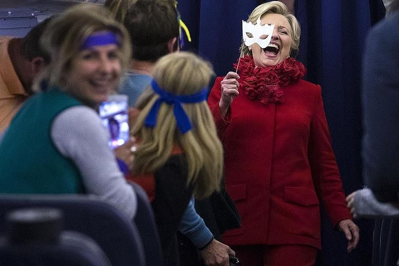 Mrs Clinton joking with her staff on a flight to Erlanger, Kentucky, during Halloween, which fell on Monday. Her campaign is working to contain the damage from FBI director James Comey's announcement that the agency was restarting a probe into the fo