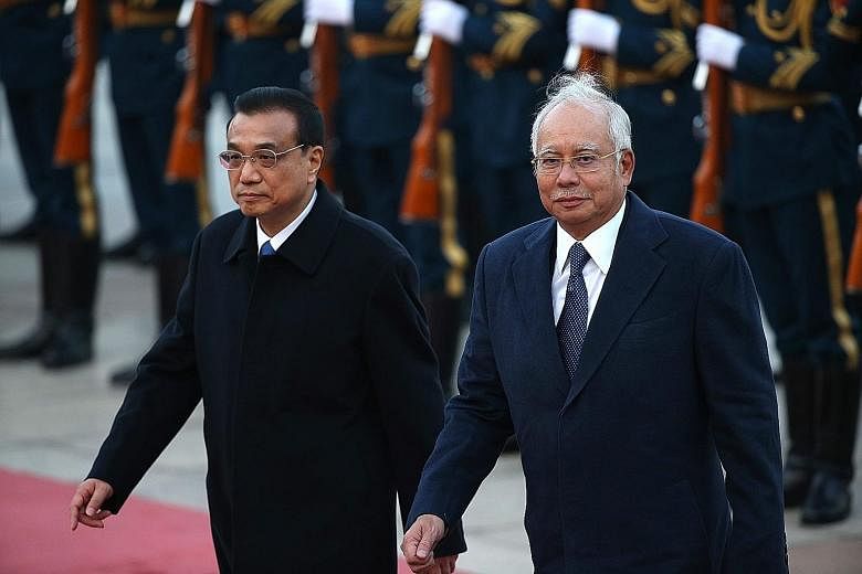 Mr Najib Razak and Mr Li Keqiang reviewing honour guards in Beijing yesterday. Nine government-to-government pacts and five business cooperation deals were signed as part of Mr Najib's visit.