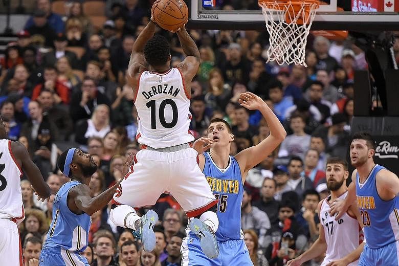 Toronto guard DeMar DeRozan takes a jump shot over Denver Nuggets centre Nikola Jokic (No. 15) and guard Will Barton in their NBA clash at the Air Canada Centre. DeRozan is the first player in Raptors' history to start a season with three straight 30