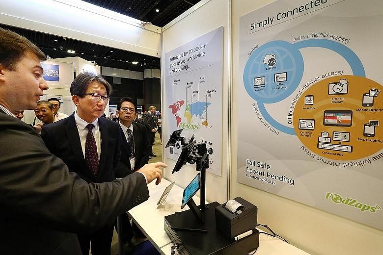 Mr Lim (centre) being shown a workflow management platform for the F&B sector at the Singapore Productivity Conference and Exhibition yesterday. The Manpower Minister said that Singapore offers a competitive proposition now, with "products and servic