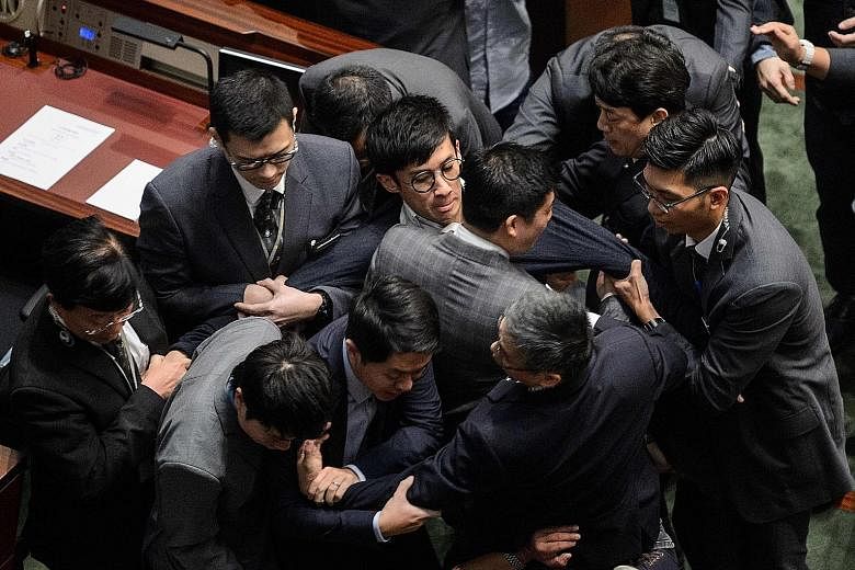 Mr Sixtus Leung (centre, wearing glasses) being restrained by security officers after attempting to recite the oath at the Legco Chamber yesterday. Describing the acts of Mr Leung and Ms Yau as violent and premeditated, the Legco president strongly c
