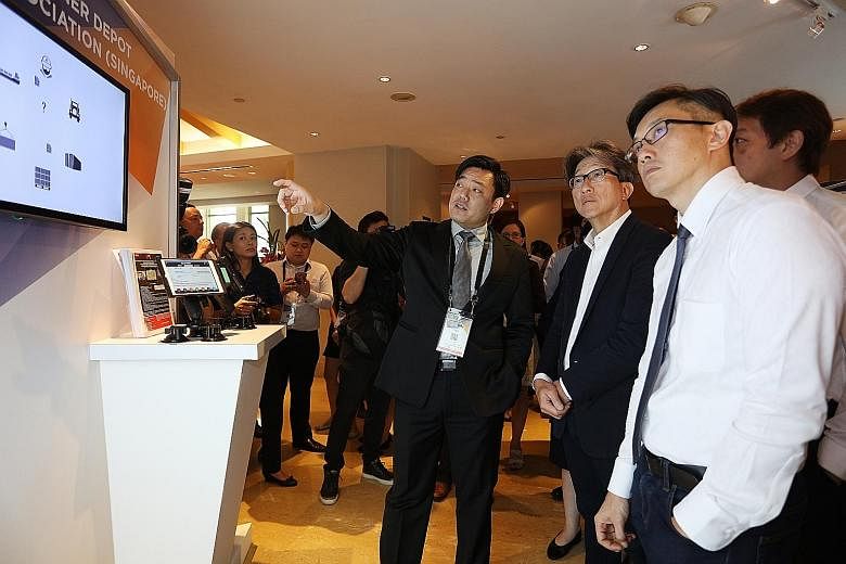 Minister of State Teo Ser Luck (right) and Manpower Minister Lim Swee Say (centre) viewing a presentation by Mr Ricky Loo from the Container Depot Association of Singapore, on new solutions adopted for container and logistics businesses.