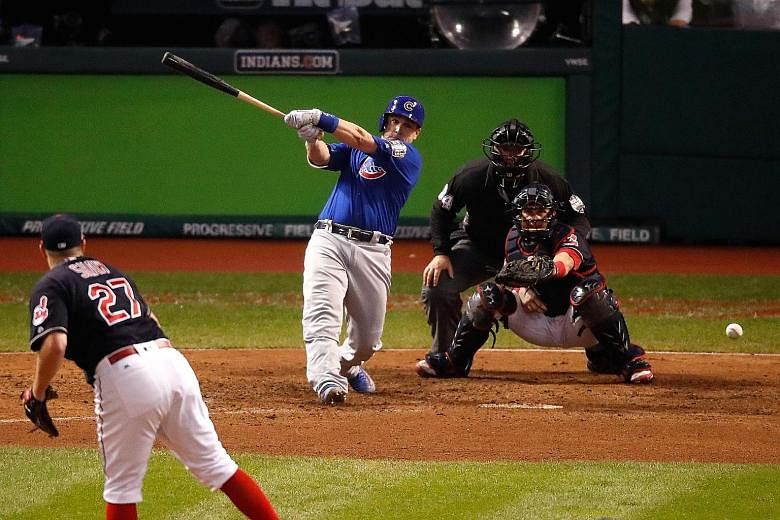 Left: The Chicago Cubs celebrate after defeating the Cleveland Indians 8-7 in Game Seven of the World Series at Progressive Field on Wednesday in Cleveland, Ohio. Below: Miguel Montero of the Chicago Cubs hits a single in the 10th inning for Anthony 