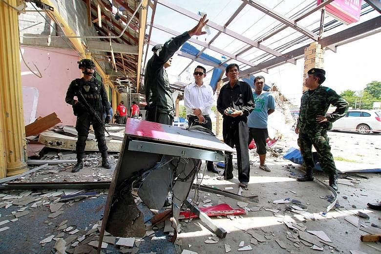 Military personnel and investigators at the site of a bomb attack in Thepha district in the troubled southern Thai province of Songkhla yesterday. At least six attacks hit Pattani, Songkhla and Narathiwat provinces.