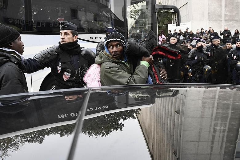 French police officers escorting migrants from the illegal camp near Paris' Stalingrad metro station yesterday. The refugees were put on buses which took them to holding centres in and around the French capital.