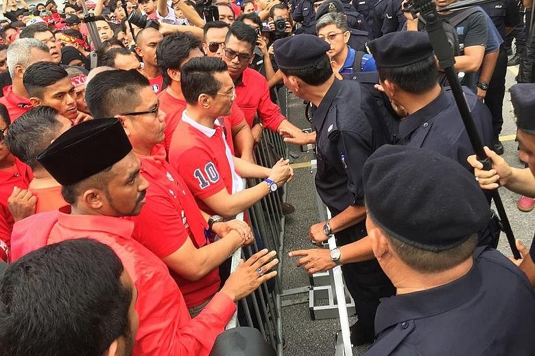 Red Shirt supporters being stopped by police near the office of Malaysiakini in Petaling Jaya yesterday. The protesters have accused the news portal of receiving foreign funds to topple Prime Minister Najib Razak's government.