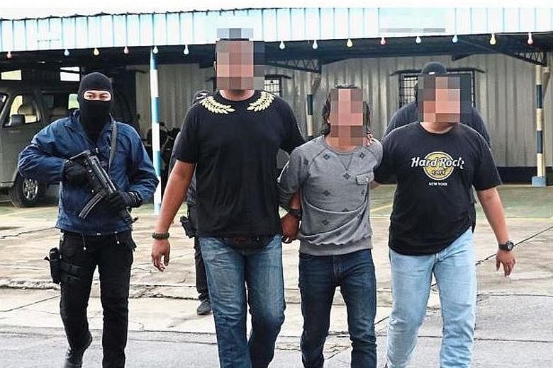 One of the Black Crow members (in light-coloured T-shirt) being escorted by police. A 29-year-old technician and a 24-year-old labourer were given about RM5,000 by Malaysia's most-wanted militant, Mohamad Wanndy Mohamad Jedi, to travel to Syria.