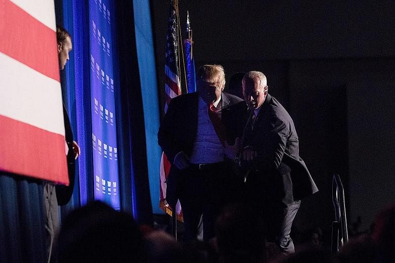 Mr Trump being rushed off the stage by Secret Service agents after someone in the crowd yelled "gun" at his rally in Reno, Nevada, on Saturday. No weapon was found on the man thought to be a threat to him, and the Republican candidate returned minute