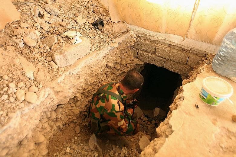 Right: One of the drills used by ISIS to bore through rock and construct tunnels. Below: A Peshmerga soldier inspecting a tunnel used by ISIS militants, on the outskirts of Bartila east of Mosul.