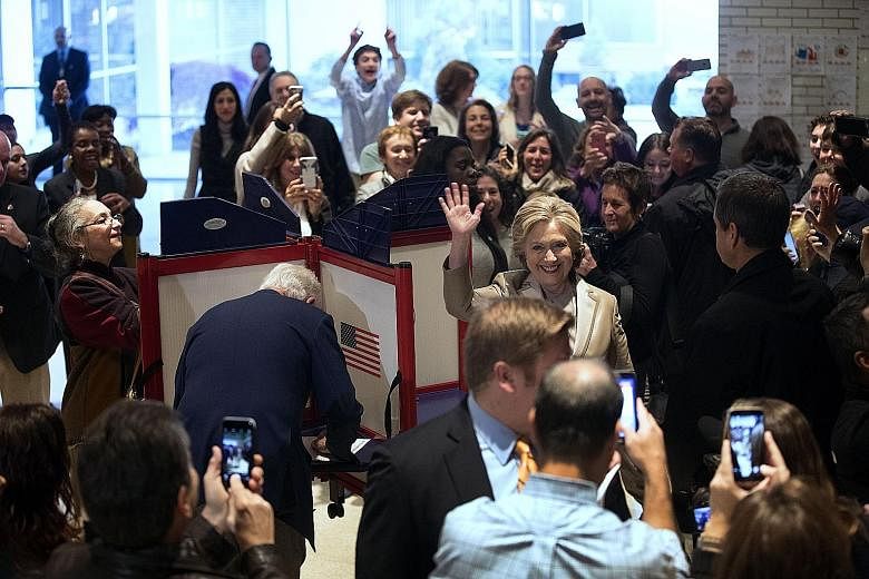 Mrs Clinton after casting her vote, while Mr Clinton (back to camera) marks his ballot slip, yesterday in Chappaqua, New York. A crowd also gathered in New York City at the polling station near Trump Tower, where Mr Trump was due to cast his vote.