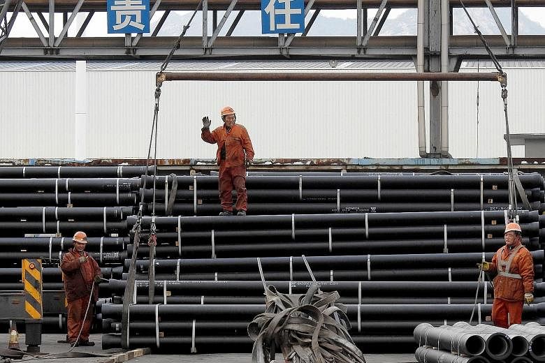 Workers loading steel tubes onto a truck at a logistics centre in Lianyungang in east China's Jiangsu province. Analysts warn that a property boom may be peaking, dampening demand for building materials from cement to steel.