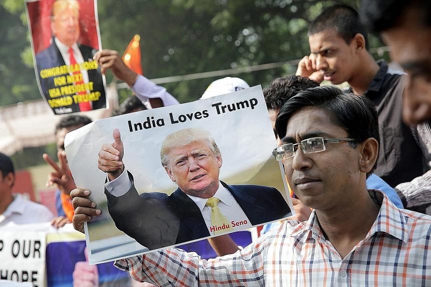 Far left: Activists from India's right-wing Hindu Sena in New Delhi yesterday celebrating Mr Trump's win. Left: A passer-by in Tokyo yesterday picking up the latest news on the US election.