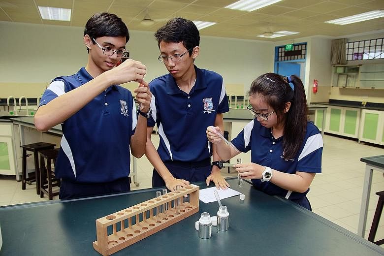 Queenstown Secondary students (from left) Zephaniah Lim, Koung Zin and Zoe Tan demonstrating how they mixed essential oils with ethanol and glycerin to create scents.