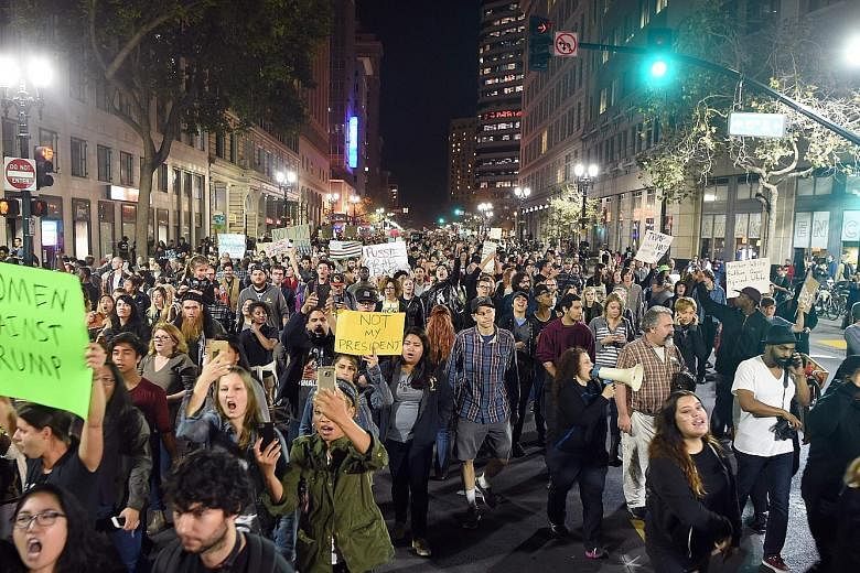 Demonstrators marching in an anti-Trump protest in Oakland, California, on Wednesday. Protesters marched in college campuses, blocked roads and surrounded Trump properties in at least 25 cities nationwide as they rallied against Mr Trump's victory in