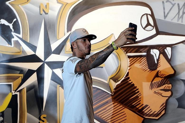 Mercedes driver Lewis Hamilton taking a selfie in front of graffiti art during a promotional event in Sao Paulo. The two-time defending champion admits that there is more of a chance he will lose the F1 title than win it and that is "hard to swallow"