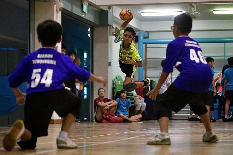 Above: Edric Soong holds the championship trophy. Right: Farrer Park Primary's right winger Ashif Rahman, 11, tries to shoot at the frame against Beacon Primary during the final of the SPH Foundation National Primary Schools Tchoukball Championship.
