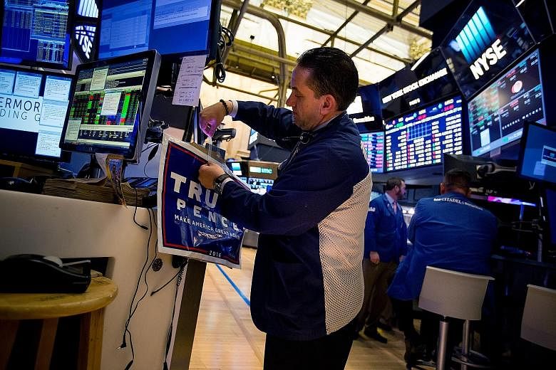 A trader taping a campaign sign, for the winning Republican ticket of Mr Donald Trump and Mr Mike Pence, to a desk on the floor of the New York Stock Exchange on Wednesday.