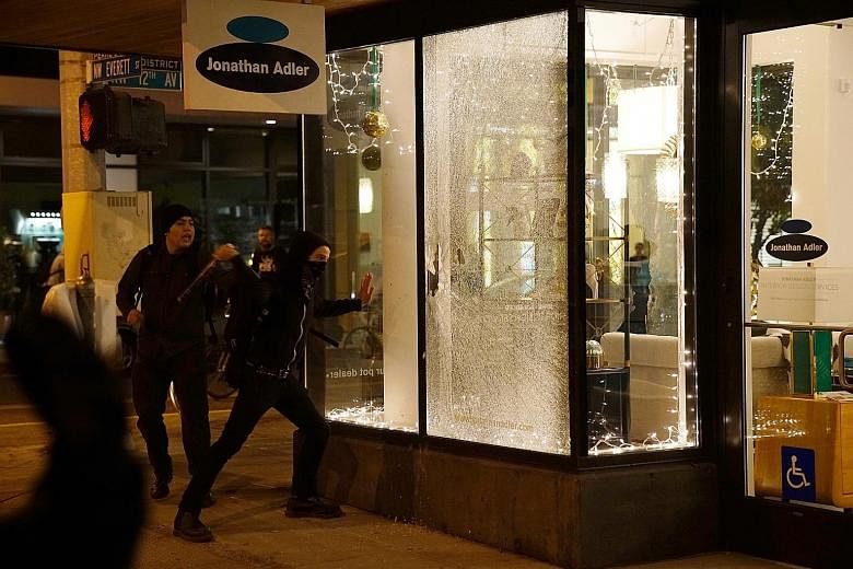 Demonstrators breaking a shop window during a protest in Portland, Oregon, yesterday against the election of Mr Trump as US President. Part of the reason for Mr Trump's historic win on Wednesday was his promise to bring back jobs to America, which he