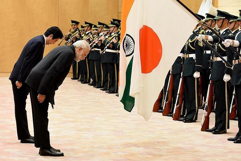 Japanese PM Abe and visiting Indian PM Modi bowing before the two countries' national flags at a review of the honour guard yesterday in Tokyo.