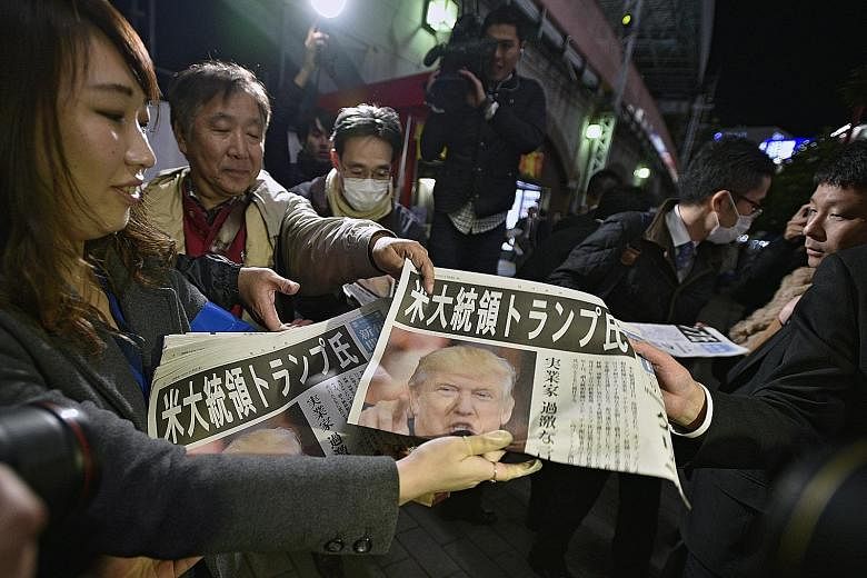 Newspapers reporting Mr Trump's election win being distributed in Tokyo. Mr Trump will meet Japanese Prime Minister Shinzo Abe in New York on Thursday.