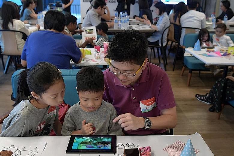 Sales manager Ang Wing Lai, 45, and his children Nicole, nine, and Jonas, four, checking out YouTube Kids during the app's launch yesterday at Google Asia-Pacific's new office at Mapletree Business City II.