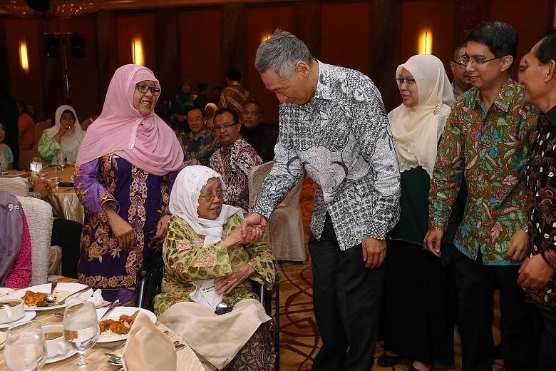 PM Lee presenting a token of appreciation to the late veteran writer Muhammad Ariff Ahmad's wife Sarinah Haniff as her daughter Shahrulbariah (left) looks on at the Arif Budiman Malay Language Teachers' Award ceremony yesterday. Behind PM Lee are Ang
