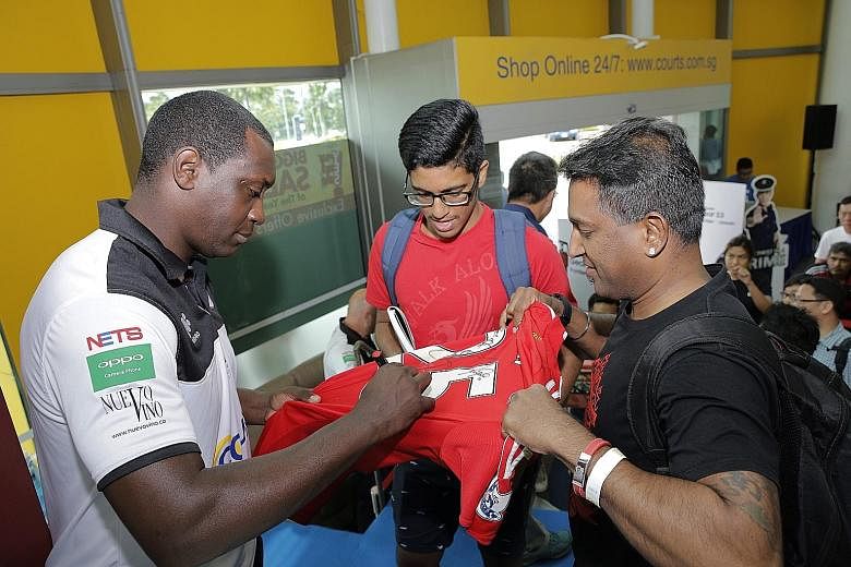 Straits Times reader Vijayarengan Visvalingam with his nephew Morhan Ramasamy getting a jersey signed by former England and Liverpool player Emile Heskey at the Courts Megastore in Tampines yesterday. Heskey was at the store to meet and greet fans al