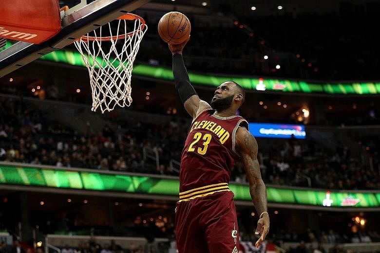 LeBron James of the Cleveland Cavaliers dunking during the 105-94 win against the Washington Wizards on Friday. During the game, James became the youngest player in NBA history to score at least 27,000 points - and was doused with water by his team-m