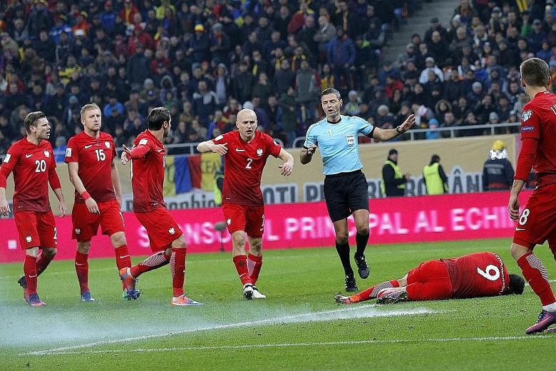 Poland captain Robert Lewandowski lies on the pitch in Bucharest after a firecracker thrown by Romanian supporters exploded about a metre away from him during the World Cup qualifier on Friday. After receiving medical treatment, he was cleared to con