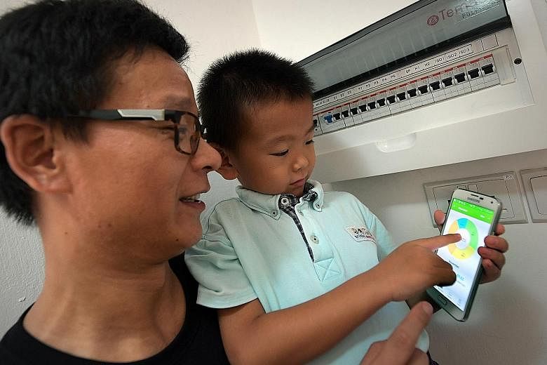 Mr Bai Zemin and his son Zhenxuan with the app that shows electrical consumption in their apartment, where the Temasek Polytechnic system is being tested.