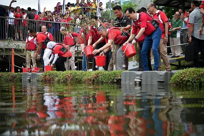 PM Lee, flanked by Dr Lam (left) and Minister of State for National Development Koh Poh Koon, planting a series of api-api putih trees on floating turfs of soil at Punggol Reservoir yesterday. The trees will have their roots suspended in the water to
