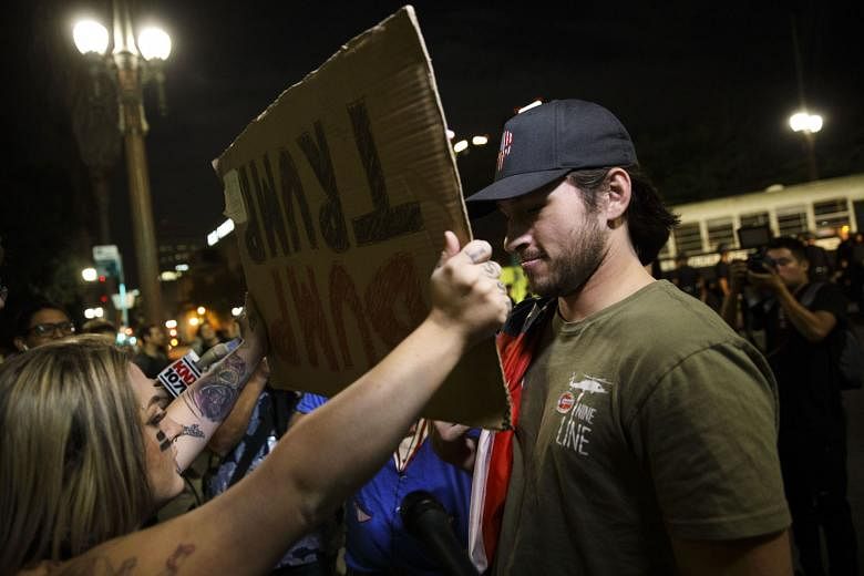 An anti-Trump demonstrator holds a sign in front of a Trump supporter during a protest near City Hall in Los Angeles last Saturday. America has to put its house in order first. 