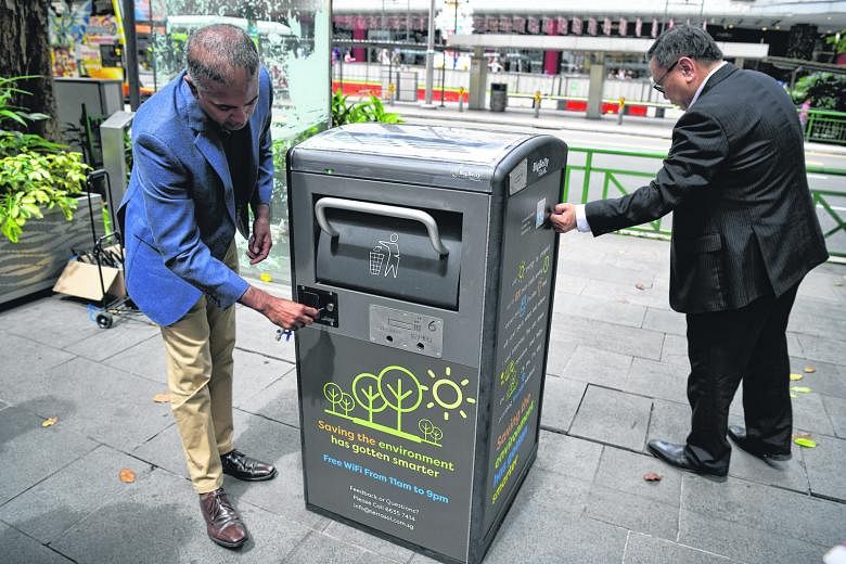 Mr Jason Kumar (left), co-founder of technology firm Terra Sol, and Orchard Road Business Association (Orba) executive director Steven Goh showing the uses of one of the solar-powered Bigbelly "smart" bins in Orchard Road yesterday. Each bin can crun