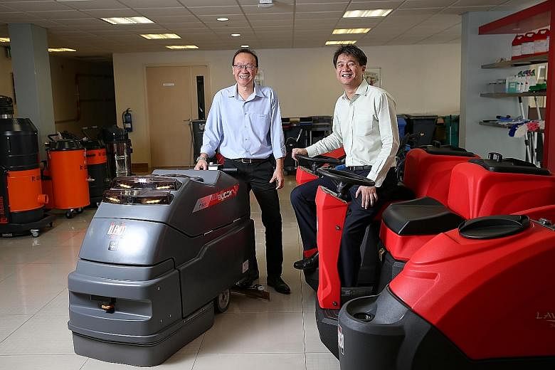 Mr Tan (far left) and Mr Beh with their robotic cleaning products. Mr Beh says the company has seen growth in demand because the use of such robots can lead to productivity gains and manpower savings.