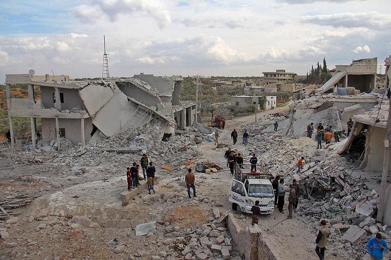 Residents in the village of Kfar Jales, near Idlib in north-western Syria, inspecting buildings that were destroyed in the air strikes by Syrian and Russian warplanes yesterday. The renewed bombardment has killed at least 20 people, including nine ch
