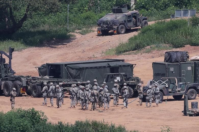Above: American soldiers taking part in a military exercise in August near the demilitarised zone separating the two Koreas in Paju, South Korea. The US has about 28,500 soldiers in the country. Below: Two US ships docked at the White Beach Naval Fac