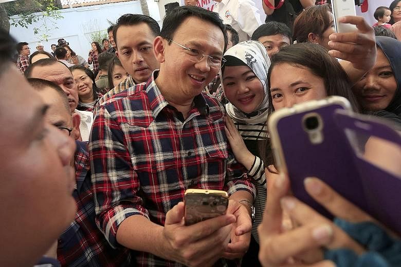 Mr Basuki taking selfies with supporters in Jakarta yesterday. The politician had been widely expected to be re-elected as Jakarta governor.