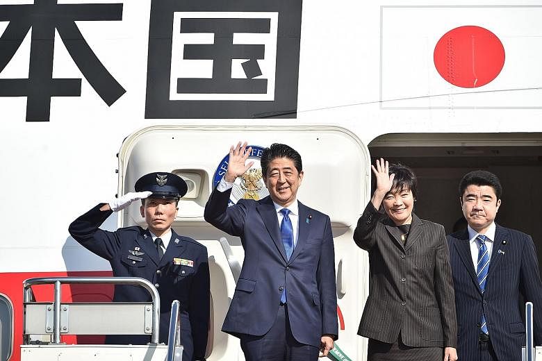 Mr Abe and his wife Akie waving to well-wishers before boarding a government plane at Tokyo's Haneda Airport yesterday. He was due to meet Mr Trump late yesterday at Trump Tower in New York. Mr Abe is the first foreign leader to meet the US President