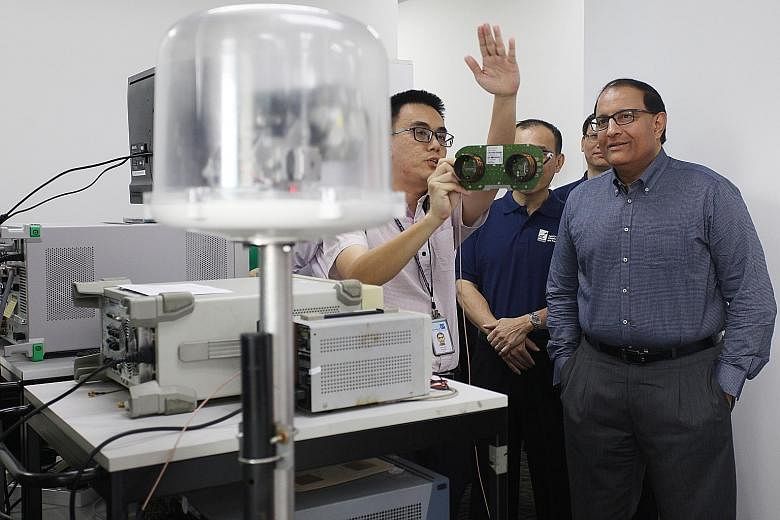 Mr Iswaran observing how a tracking antenna, commonly used in vehicular deployment, responds to a simulated beacon signal in a demonstration by Addvalue Technologies engineer Choong Yoon Hui.