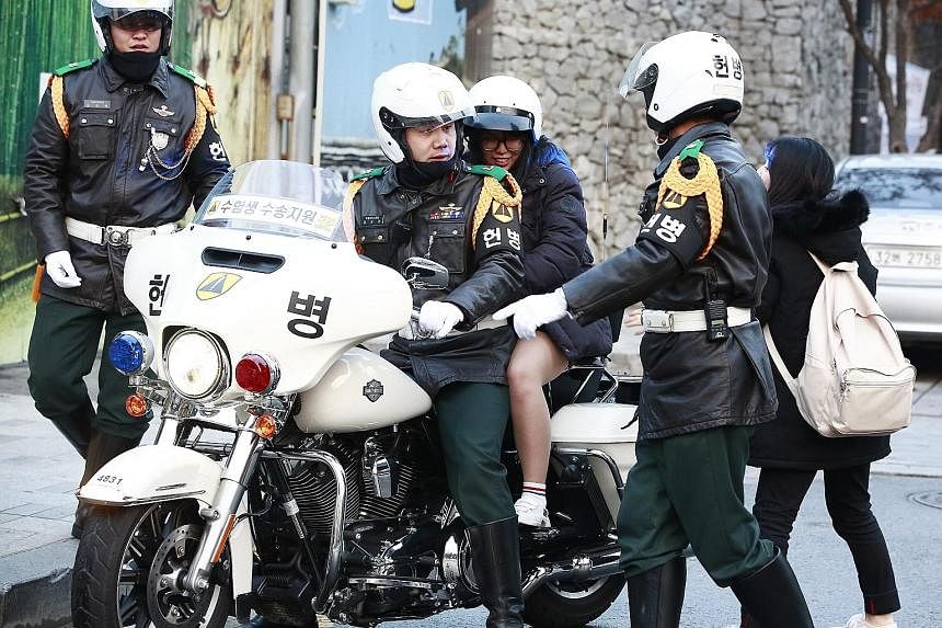 Policemen in Seoul giving a lift to a student taking a crucial college entrance examination yesterday. About 606,000 students in South Korea took the high-stakes annual examination that could earn them a place in one of the elite colleges seen as key