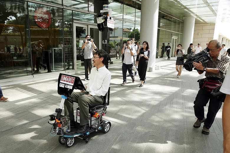 Dr Ang demonstrating how the self-driving mobility scooter works at NUS' University Town yesterday. The Singapore-MIT Alliance for Research and Technology harnessed previously developed software for driverless cars and buggies for use in the scooter,