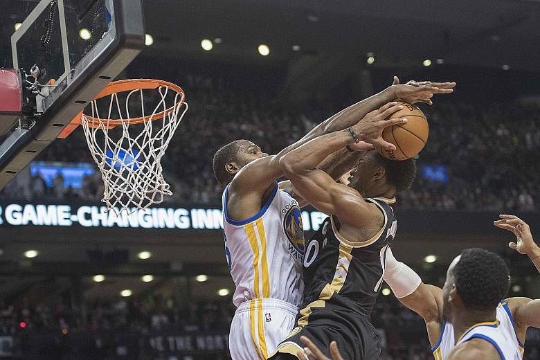 Toronto Raptors guard DeMar DeRozan (middle) drives to the basket as Golden State Warriors forward Kevin Durant (left) attempts to block his shot during the third quarter on Wednesday. The Warriors won 127-121 as Durant and Stephen Curry combined for