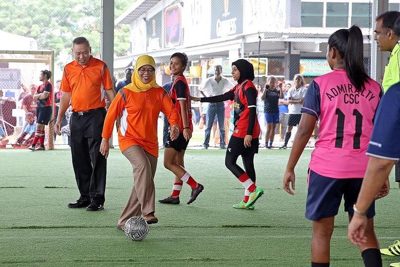 Madam Halimah kicking off a futsal match yesterday at Woodlands Recreation Centre, flanked by Mr Lim Hock Chee, the vice-chairman of the Marsiling Citizens' Consultative Committee.