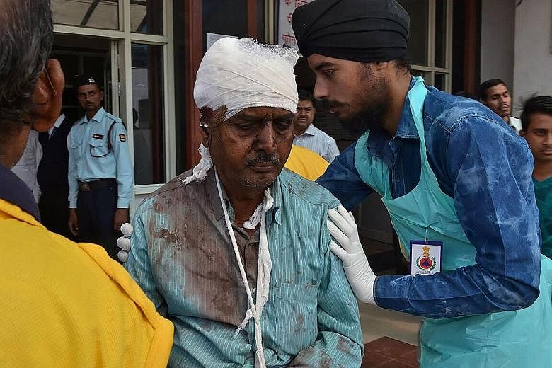 Above: An injured passenger receiving treatment at a hospital in Kanpur yesterday following the deadly accident. Above, right: Rescue workers at the site of the derailment in Pukhrayan, south of Kanpur city, India.